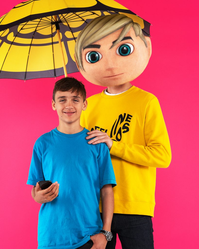 Två personer mot cerise bakgrund en håller i ett paraply och en ung kille håller i en mobiltelefon