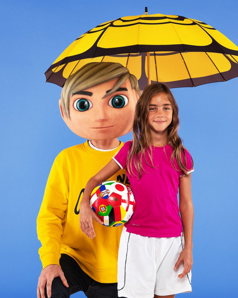 Två personer mot blå bakgrund en håller i ett paraply och en ung flicka håller i en fotboll